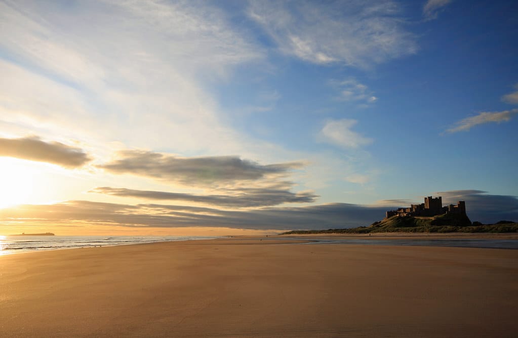 Bamburgh Castle standing above the sand dunes and beach on the Northumberland coast